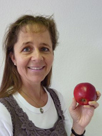 Das Bild zeigt eine Frau die einen Apfel in der Hand hält nund in die Kamera lächelt.