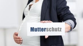 Eine schwangere Frau hält ein Schild mit der Aufschrift "Mutterschutz"