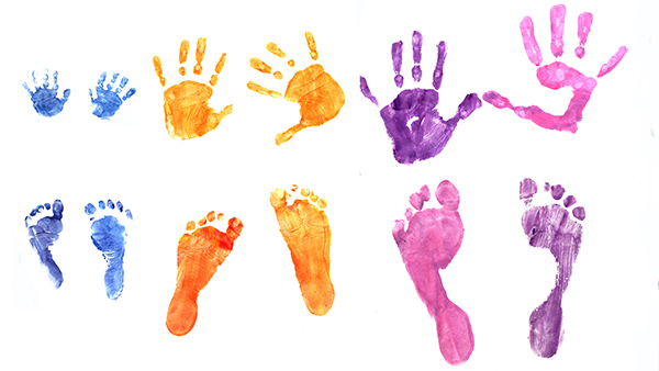 Bunte Hand- und Fußabdrücke von Kindern auf weißem Papier