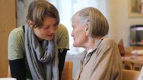 Eine ambulante Pflegerin unterhält sich mit einer Seniorin.