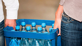 Zwei Hände tragen einen blauen Kasten mit Wasserflaschen.