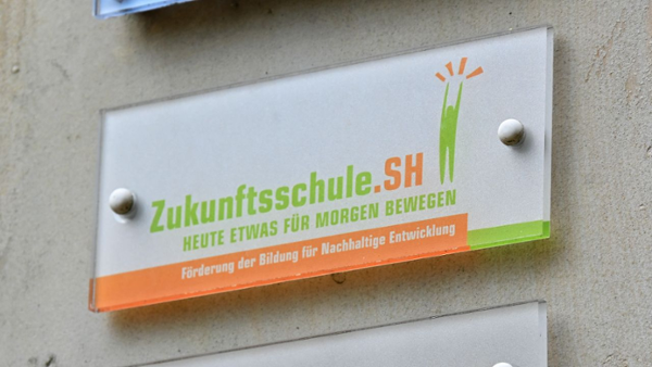 Eine Plakette mit der Aufschrift "Zukunftsschule.SH" an der Wand eines Schulgebäudes