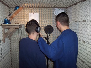 Zwei Gefangene stehen in einem, mit Eierkarton gedämpften kleinen Raum und nehmen Musik auf