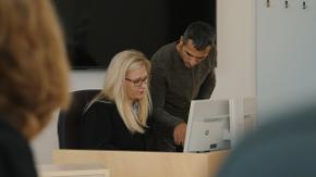 Eine Frau und ein Mann sitzen vor einem Computer.