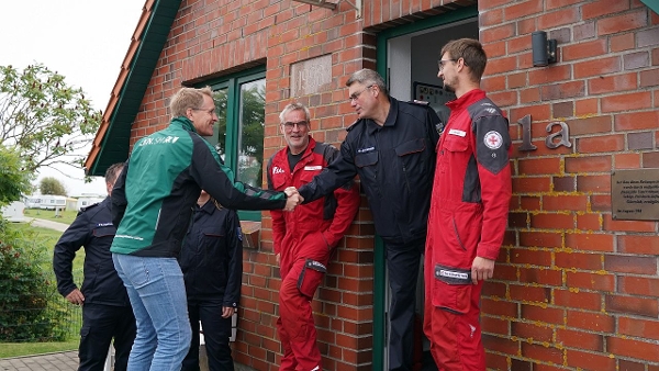 Zwei Männer geben sich die Hand. Daneben stehen zwei weitere Männer in roten Anzügen. (Quelle: Staatskanzlei) Zwei Männer geben sich die Hand. Daneben stehen zwei weitere Männer in roten Anzügen.