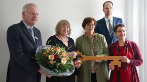 Die Ministerinnen Heinold und Sütterlin-Waack halten gemeinsam mit einer weiteren Frau einen großen Schlüssel in der Hand. Neben ihnen stehen zwei Männer. 