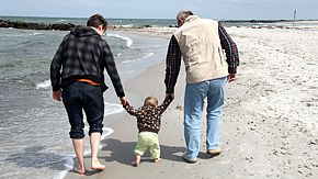 Kind mit Papa und Opa am Strand.