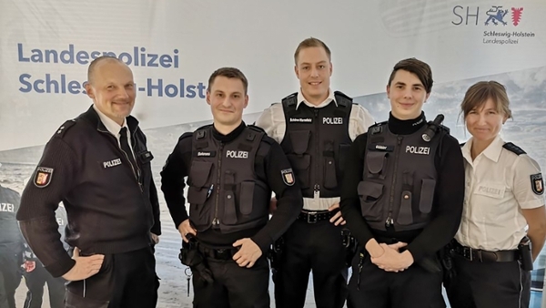 Bild zeigt 5 Polizeibeamte vor einer Messewand