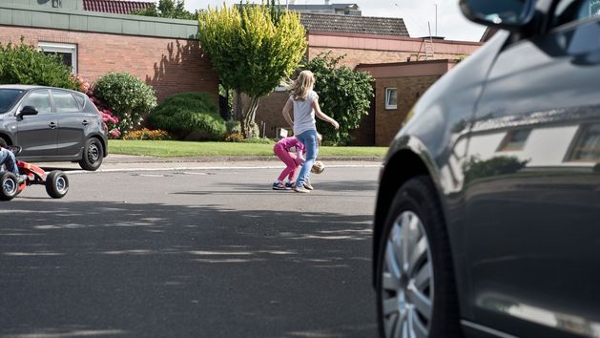 Kinder spielen auf einer Straße mit einem Ball