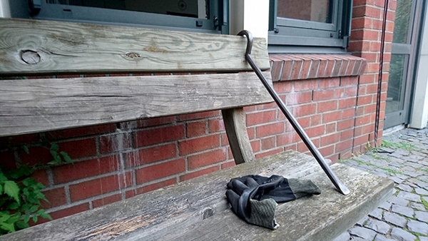 Bild zeigt einen Kufuß und ein paar Handschuhe, die auf einer Holzbank liegen, die vor einem Haus steht.