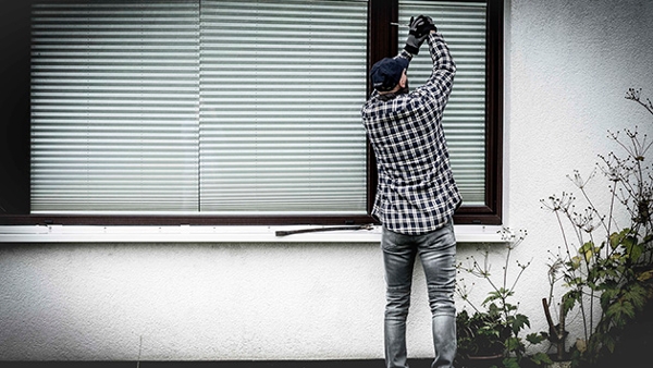 Bild zeigt eine Person, die versucht, ein Fenster aufzuhebeln.