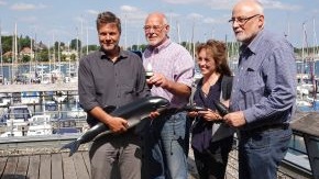 Vier Menschen stehen auf dem Dach des Ostsee Informations-Centers in Eckernförde. Robert Habeck hält eine Schweinswal-Atrappe in der Hand. Wolfgang Albrecht ein PAL-Gerät.