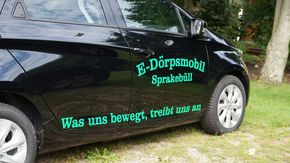 Ein Auto mit der Aufschrift 'E-Dörpsmobil Sprakebüll - Was uns bewegt, treibt uns an.'