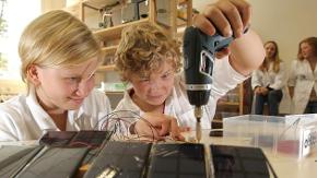 Zwei Kinder verschrauben kleine Solarzellen im Klassenzimmer.