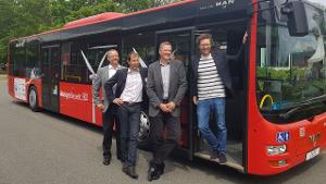 Minister Albrecht lehnt sich aus der Tür eines stehenden Busses. Neben ihm stehen Vertreter eines Unternehmens.