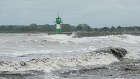 Ostseebrandung mit Leuchturm im Hintergrund