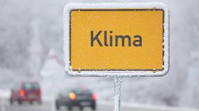 Ein Ortseingangsschild mit dem Namen Klima ist vor einer stark befahrenen Straße zu sehen.