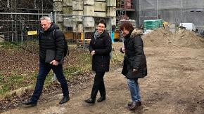 Finanzministerin Heinold geht mit einem Mann und einer Frau über eine Baustelle. 