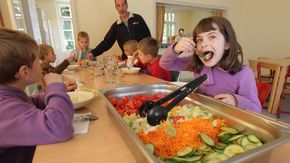 Grundschulkinder sitzen an einem Tisch und essen gemeinsam.