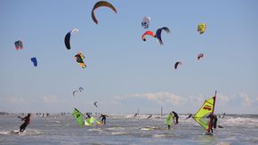 Eine Gruppe Kitesurfer auf ihren Brettern.