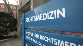Ein Schild mit der Aufschrift "Rechtsmedizin" vor einem Gebäudeeingang.
