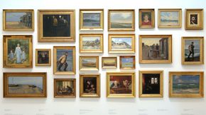 Viele Bilderin goldenen Rahmen hängen an einer Wand.