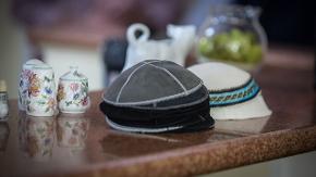 Mehrere Kippas und einige Gefäße auf einer Bank