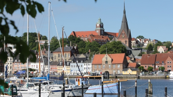 Eine Ansicht der Flensburger Nordstadt vom Ostufer der Förde. Im Vordergrund liegen Segelboote.