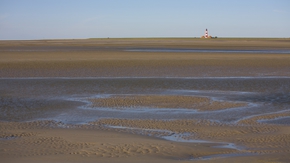 Blick über das Watt bei Ebbe, in der Ferne der Westerhever Leuchtturm