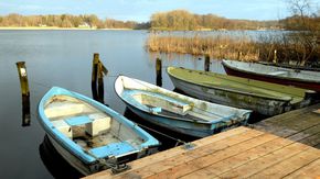 Vier Ruderboote liegen an einem Bootsanleger im Westensee