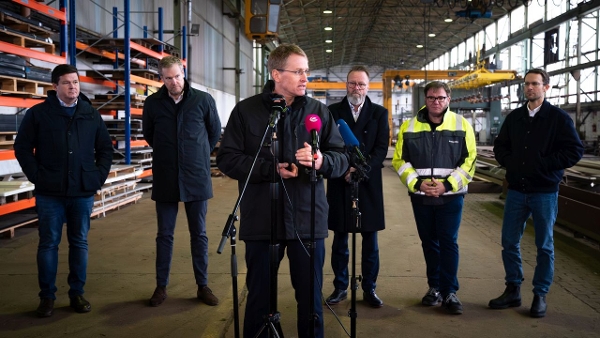 Ministerpräsident Günther steht in einer Werfthalle vor einigen Mikrofonen. Hinter ihm stehen Gewerkschaftsvertreter, Insolvenzverwalter und Wirtschaftsminister Madsen. (Quelle: Staatskanzlei) Ministerpräsident Günther steht in einer Werfthalle vor einigen Mikrofonen. Hinter ihm stehen Gewerkschaftsvertreter, Insolvenzverwalter und Wirtschaftsminister Madsen.