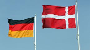 Eine deutsche und eine dänische Flagge wehen nebeneinander an zwei Fahnenmasten.