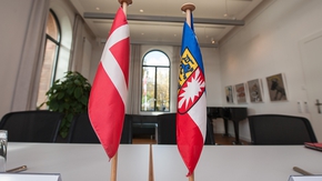 Die Flaggen von Schleswig-Holstein und Dänemark stehen auf einem Tisch