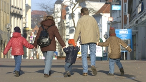 Eltern gehen mit ihren drei Kindern an der Hand in der Flensburger Innenstadt spazieren. 