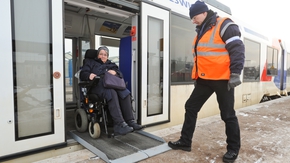 Eine Rollstuhlfahrerin verlässt einen Nahverkehrszug über eine ausgeklappte Rampe