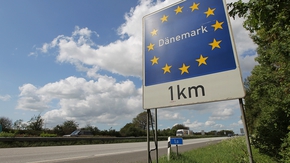 Blick auf ein Autobahnschild, das anzeigt, dass die dänische in 1 km Grenze erreicht wird. 