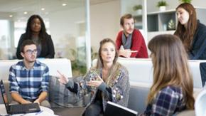 Junge Menschen diskutieren in lokkerer Runde bei der Arbeit.